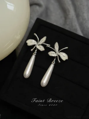 White orchid pearl drop earrings with silver-tone floral details displayed on a black jewelry tray, elegant Chinese earrings for Hanfu and Cheongsam styling