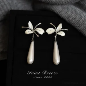 Top view of white orchid drop pearl stud earrings arranged on a black tray, delicate Chinese floral jewelry for Hanfu and Qipao outfits