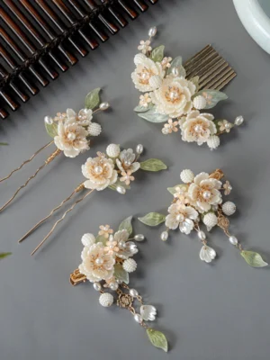 White peony Hanfu hair accessories set flat lay with floral hair comb, pearl tassel clips, U-shaped hairpins, green leaves, and gold-tone details