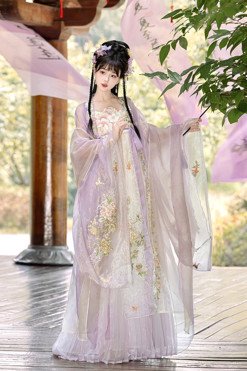 Soft lavender Tang Dynasty Hanfu Heziqun dress with intricate floral embroidery and sheer outer cape beside a wooden pavilion
