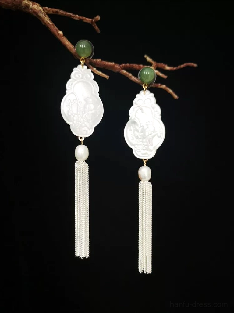 Pair of white shell Chinese earrings with long silver tassels, pearl details, and green jade accents on a black background