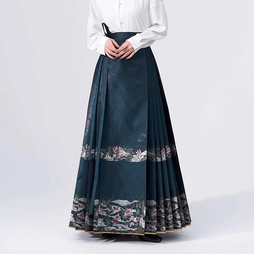 White stand-collar Hanfu blouse styled with a dark teal mamian skirt featuring lotus landscape embroidery and gold trim