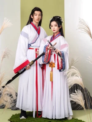 Front full-body view of a male and female Wei Jin xianxia hanfu couple wearing matching white hanfu sets with red and blue geometric trim, red waist sashes, pleated skirts, and traditional fantasy styling
