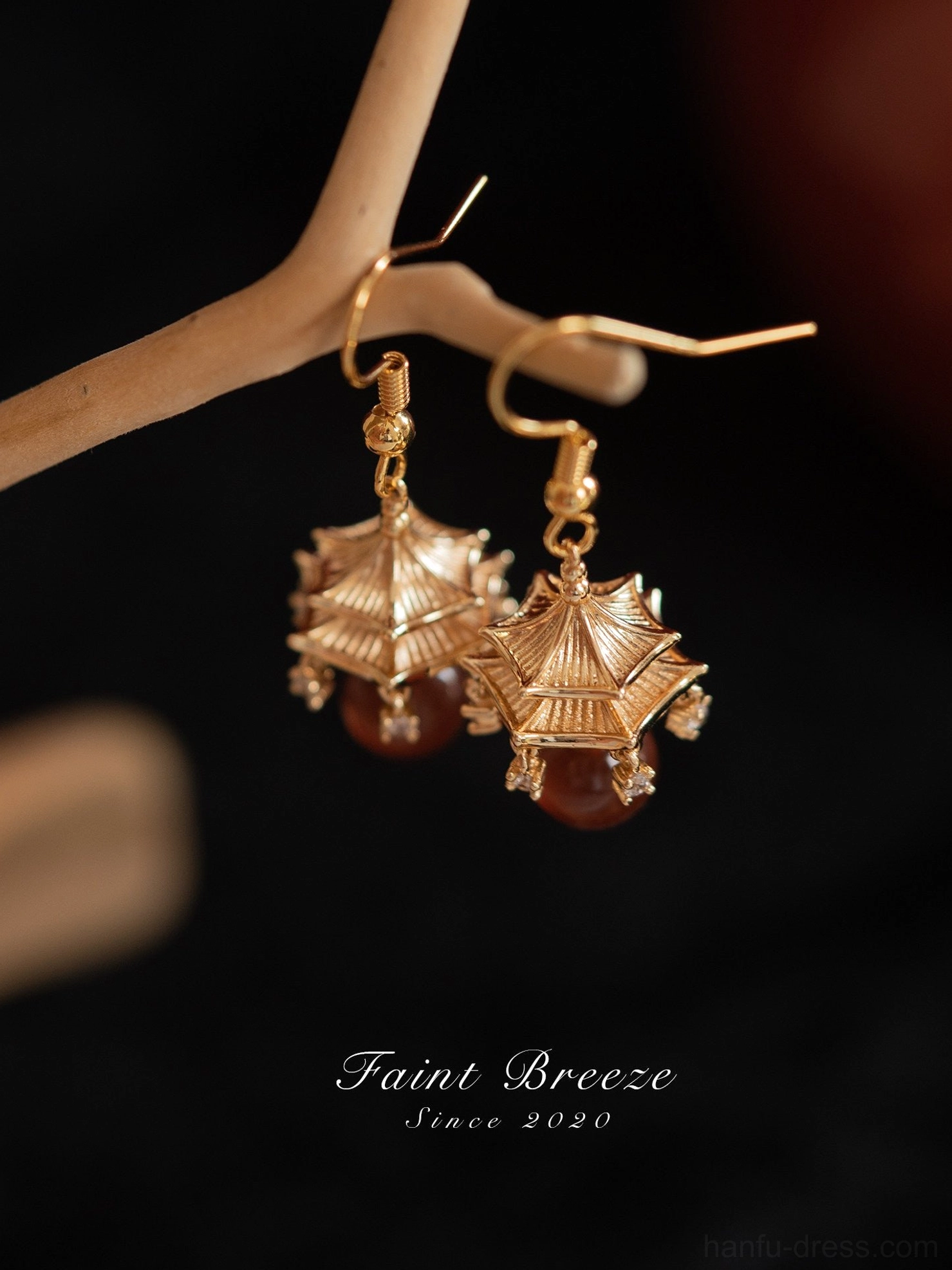 Angled close-up of gold Chinese pavilion drop earrings with textured roof detail and clear crystal accents for Hanfu and Qipao