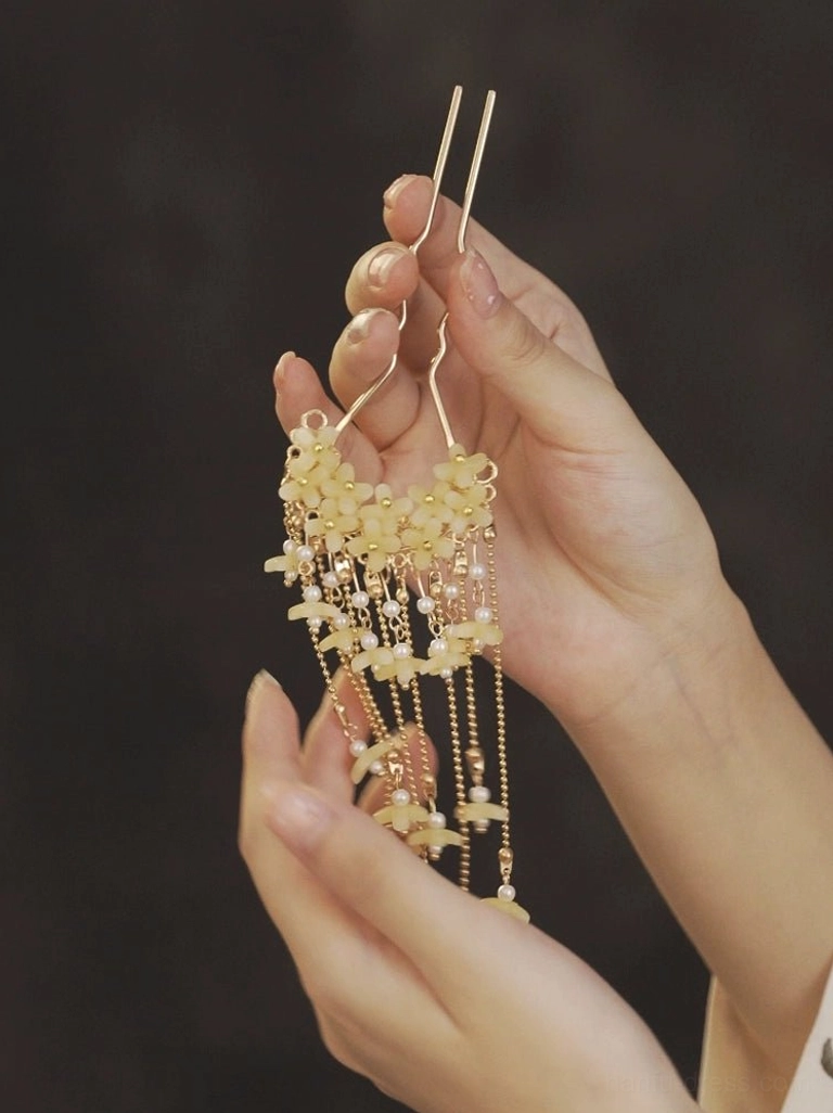 Detailed handheld view of traditional Chinese floral tassel hair fork showing pearl like dangling ornaments and twisted double prongs