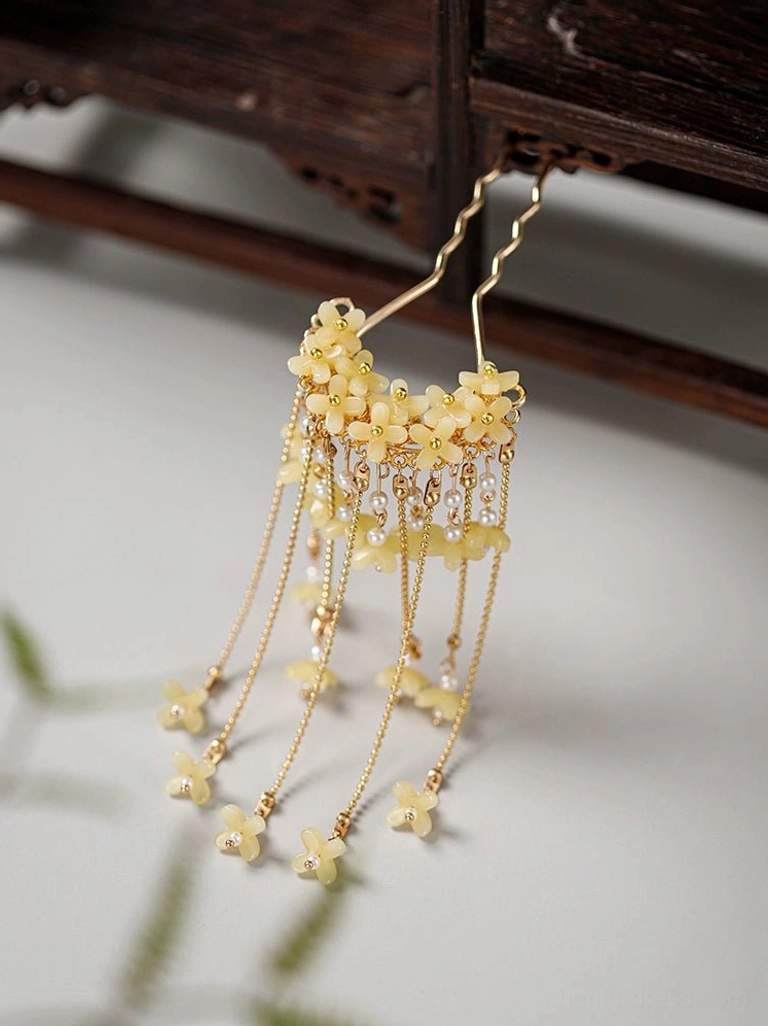 Side view of Chinese traditional wind chimes floral tassel hair fork on vintage wood with creamy flower cluster and gold tone tassels