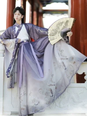 Male model wearing Wind Elegance purple ombre Wei Jin Hanfu for men with cross collar, wide sleeve outer coat, cloud embroidered wrap skirt and folding fan