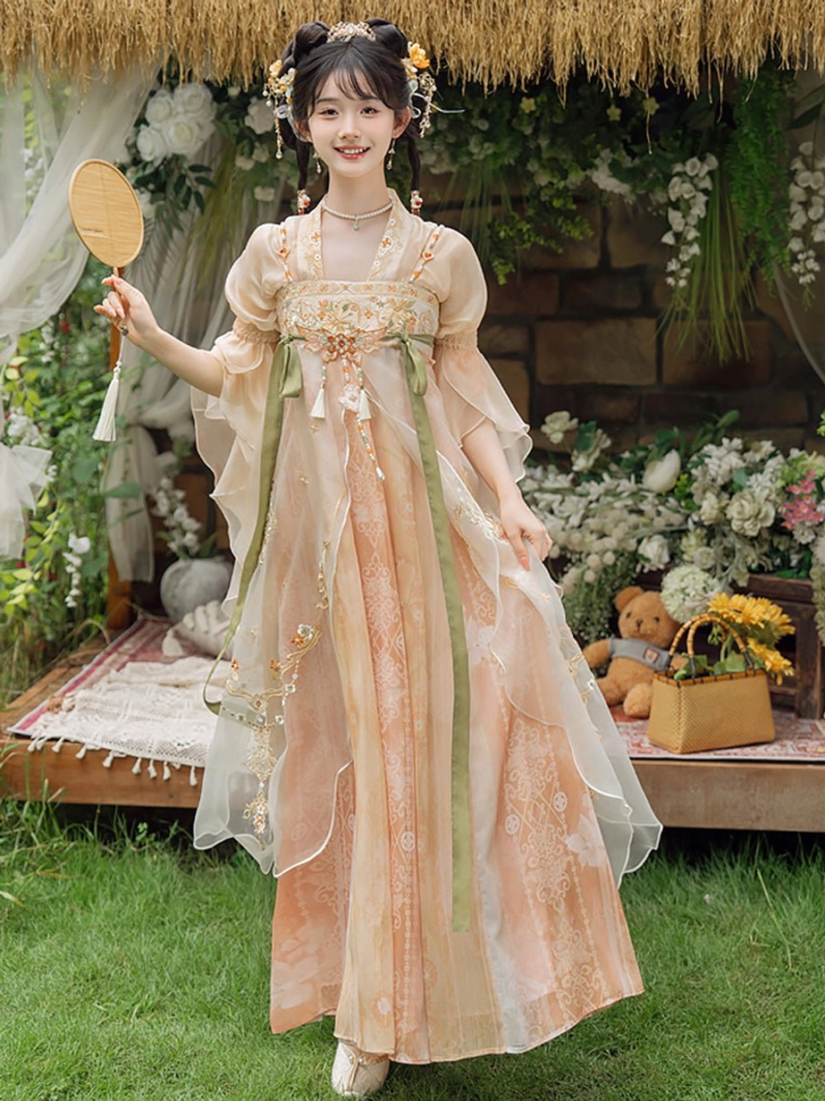 Full front view of a Tang Dynasty style qixiong Hanfu dress with sheer apricot gradient fabric, floral embroidery, flutter sleeves, green ribbons, and tassel ornaments