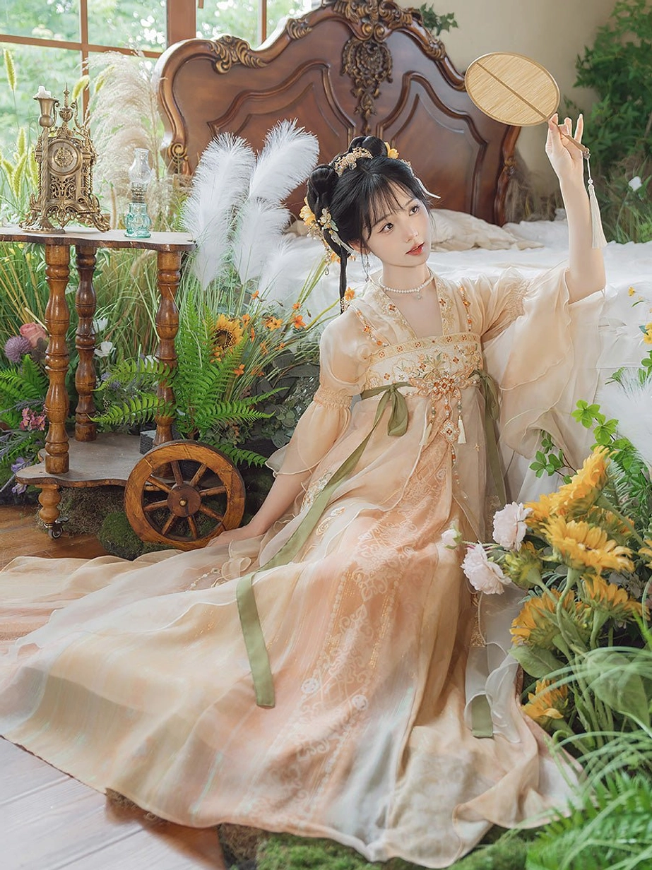 Side view of a Tang Dynasty qixiong ruqun Hanfu dress with flowing apricot organza-style skirt, wide flutter sleeves, green waist ribbons, and chest embroidery