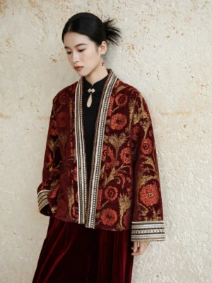 Female model wearing a wine red modern Hanfu jacket with golden floral jacquard patterns, embroidered front trim, drop shoulder sleeves, black inner top, and retro wide leg pants