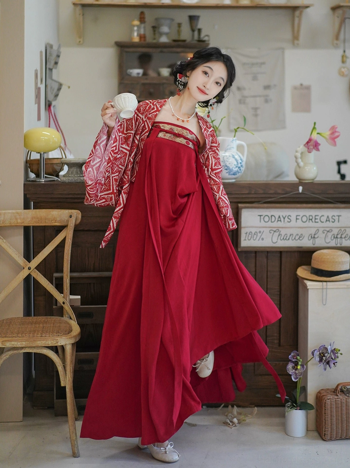 Three-quarter view of a wine-red modern Hanfu dress and cropped Tang-inspired cardigan with a softly flowing skirt and vintage tea setting