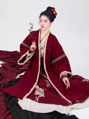 Wine red Song Dynasty modern hanfu outfit shown in a seated view with layered skirt, striped sleeve details, floral embroidery, and plum blossom styling