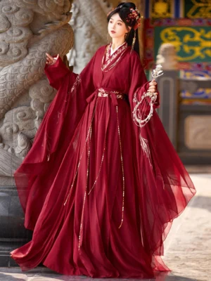 Wine red traditional Chinese Hanfu dress shown from a three-quarter side view with floor-length chiffon skirt, embroidered waist belt and long hanging tassels