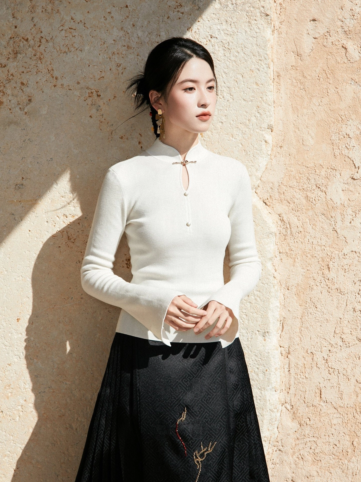 White Chinese style ribbed wool sweater with stand collar frog button detail and flared cuffs three-quarter view