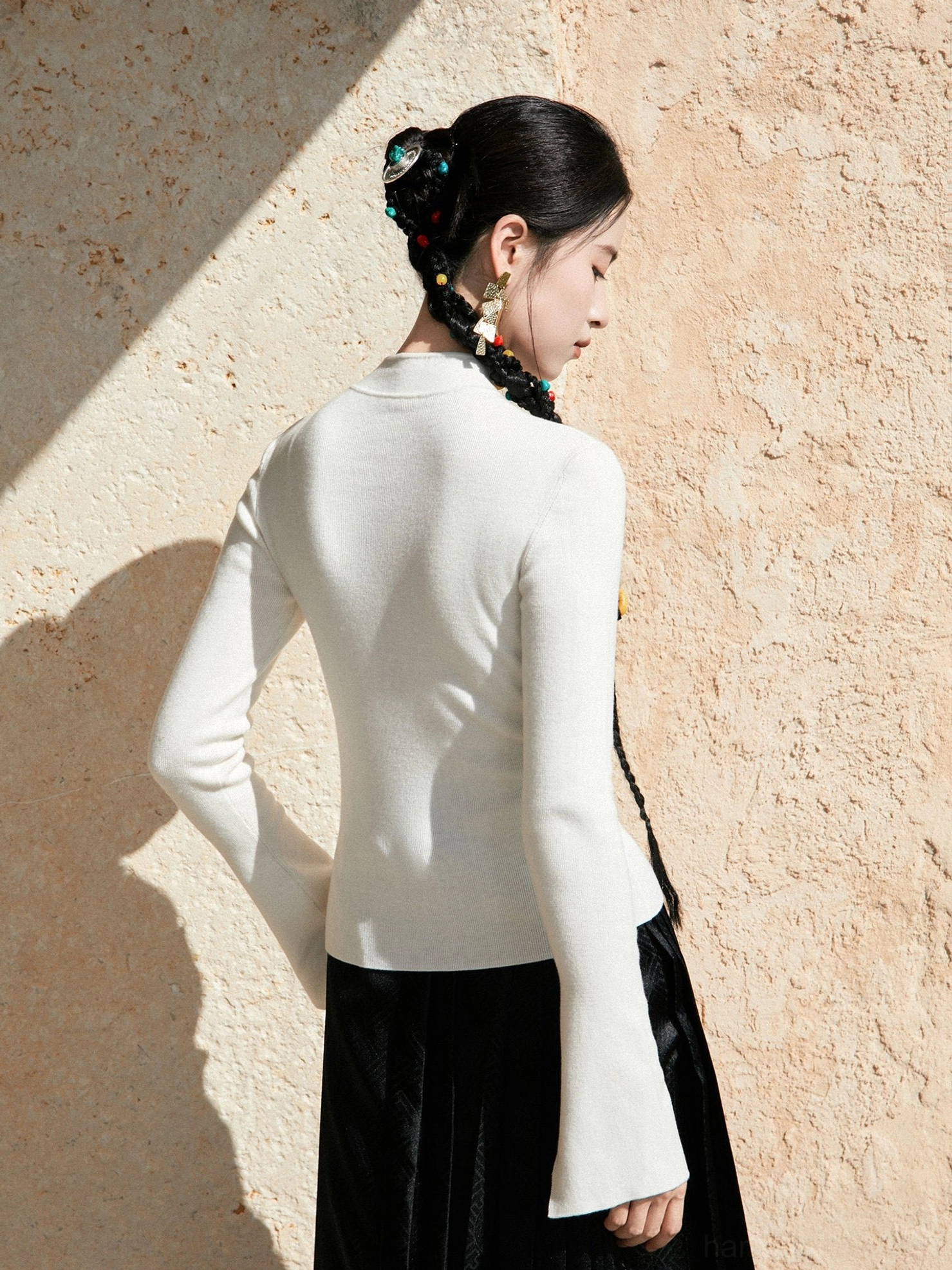 Back view of white modern Hanfu fitted wool knit top with ribbed texture and flared long cuffs styled with embroidered mamian skirt