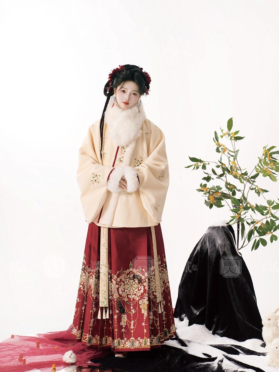 Winter Ming Dynasty Hanfu dress with beige fur-collar top, red embroidered mamian skirt, white hand muff, and traditional hairstyle