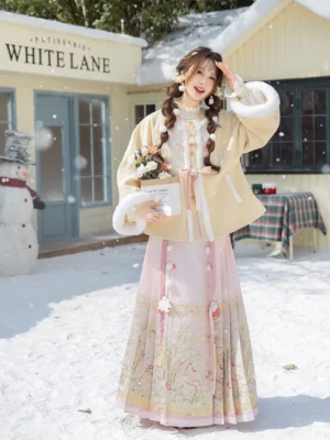 Full body view of a winter Ming Dynasty Hanfu set with beige fleece trimmed jacket and pink floral embroidered Mamian skirt worn outdoors in snow
