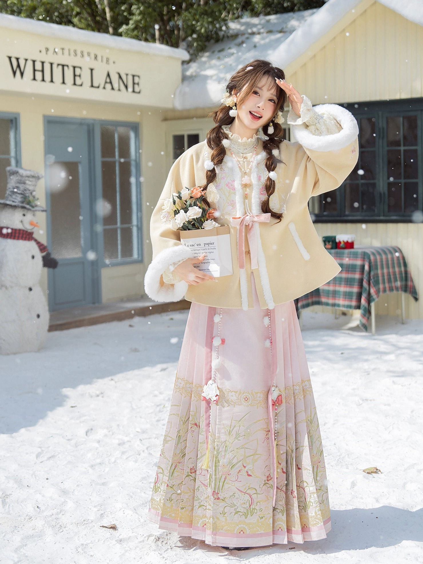 Full body view of a winter Ming Dynasty Hanfu set with beige fleece trimmed jacket and pink floral embroidered Mamian skirt worn outdoors in snow