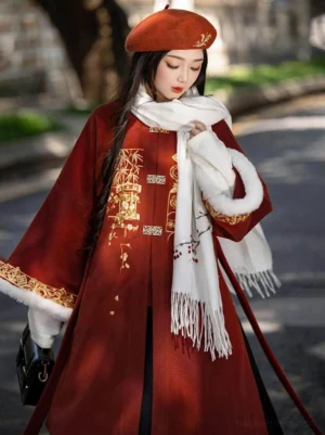 Half-body view of a winter Ming style Hanfu overcoat featuring gold Four Gentlemen Sijunzi embroidery, white fur trimmed cuffs, long red waist sashes, and Chinese New Year fashion details