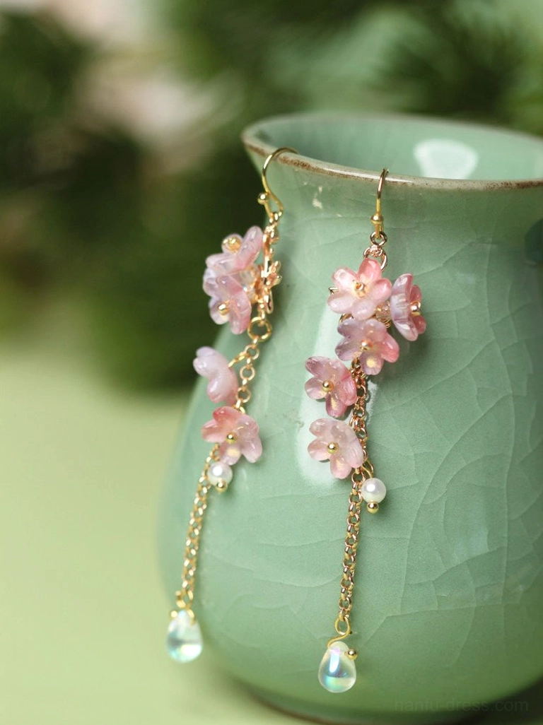 Hook style wisteria glazed flower drop earrings with cascading gold tone chains, pearl beads and shimmering teardrop pendants on celadon vase