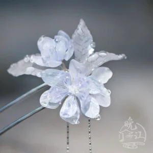 Front close-up of a pale blue translucent flower Chinese hair stick with layered petals, leaf ornaments, dual metal hair sticks, and delicate bead tassels