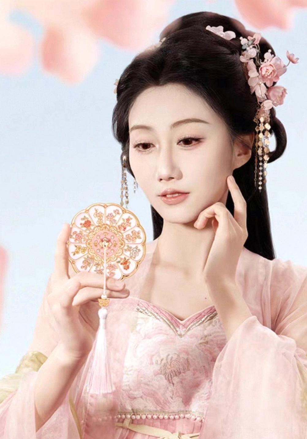 Woman in pink traditional Hanfu holding a Twelve Flower Goddesses Chinese hand mirror beside her face
