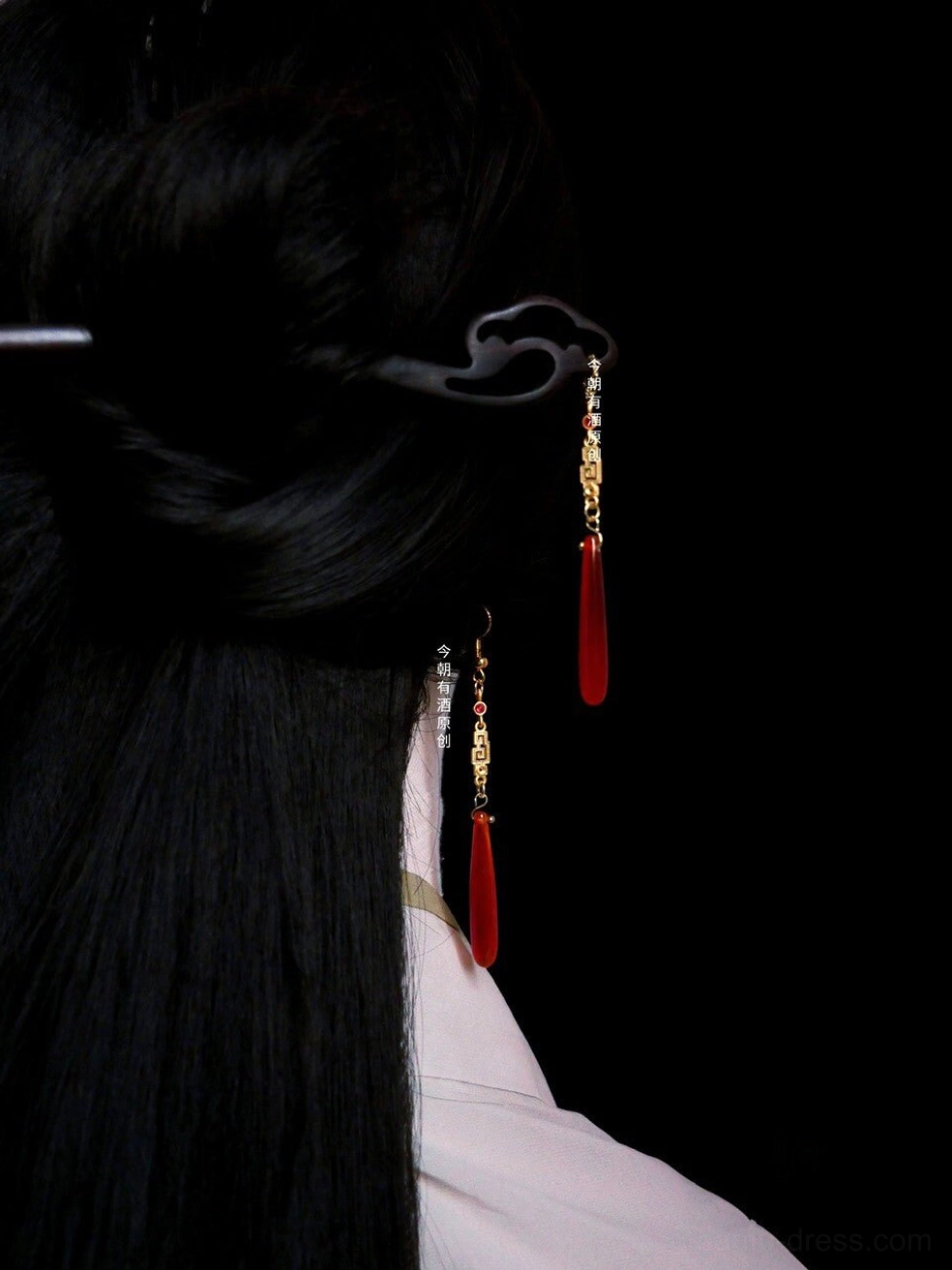 Woman wearing red agate Chinese earrings with gold fretwork details and a light pink Hanfu collar, shown with a traditional black hairpin