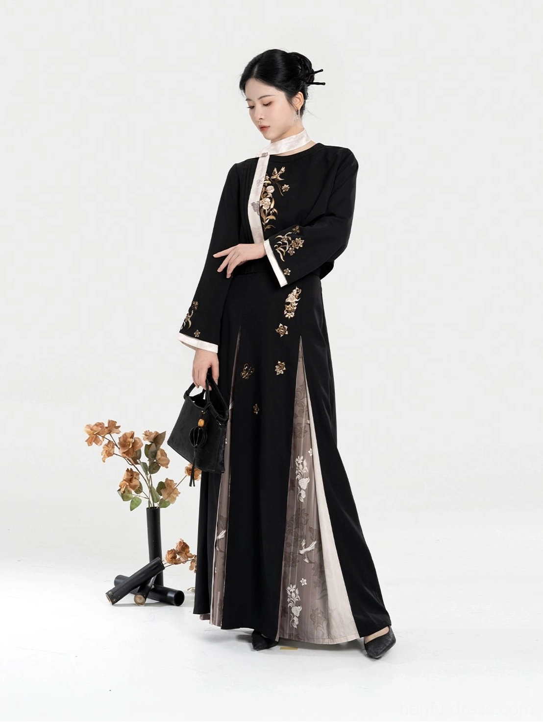 Three-quarter side view of a women's embroidered Chinese-style Hanfu set with black cropped jacket, white collar trim, golden flowers, and layered maxi skirt