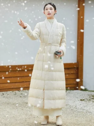 Women’s Hanfu-inspired 90 percent white duck down long coat worn in a snowy traditional courtyard with quilted panels and plush cuffs