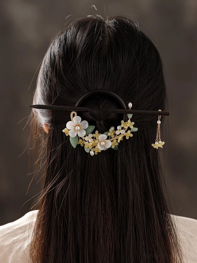 Woman wearing a wooden osmanthus Hanfu hair pin with white flowers yellow blossoms green leaves and pearl tassel in a traditional updo