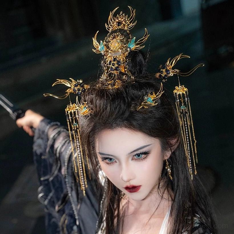 Close-up of Xi Wei gold-tone Hanfu crown with blue enamel-style floral details and long chain tassel hairpins worn in an elegant updo