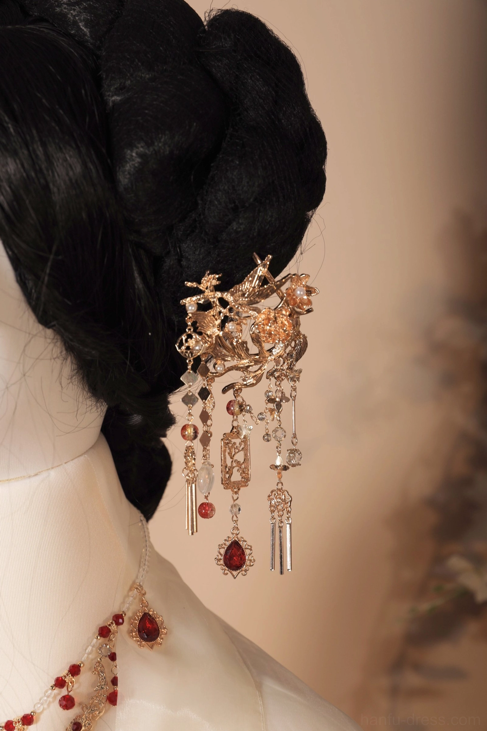 Close-up rear view of a vintage Chinese wedding hair pin worn in a traditional black hair bun, featuring carved gold-toned metal, burgundy gemstones, and layered hanging tassels