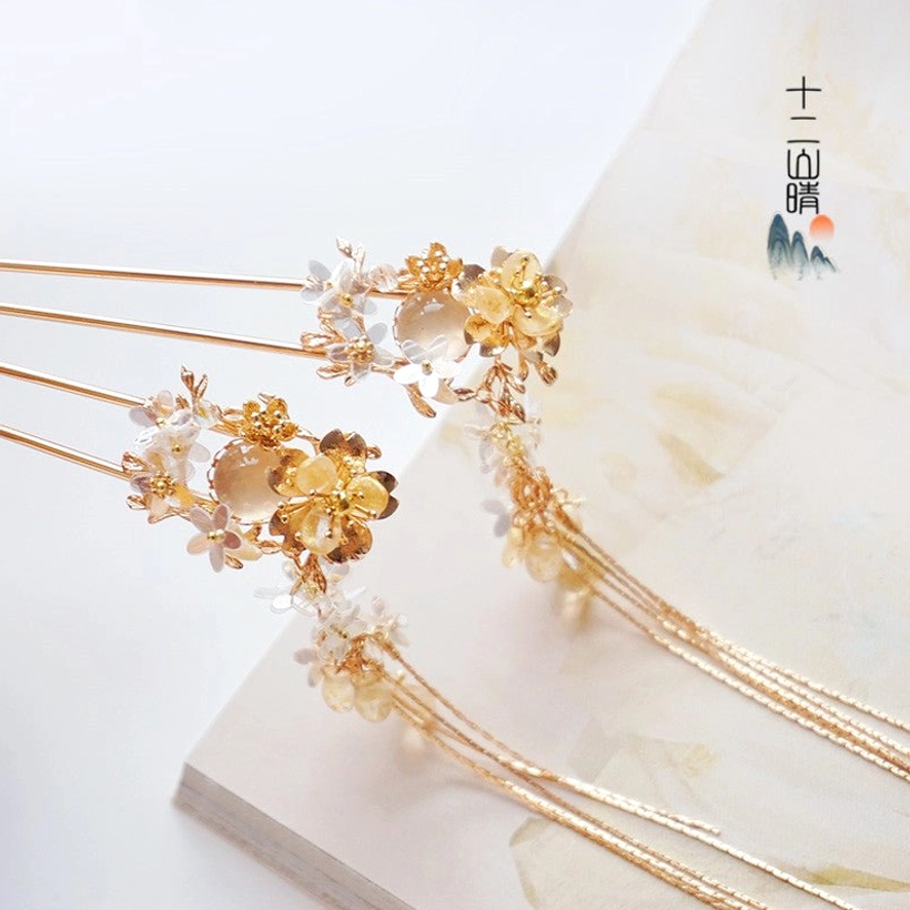 Xiangling gold floral tassel hair pins with blue purple flowers cat-eye style beads and long chain tassels displayed on vintage stationery background