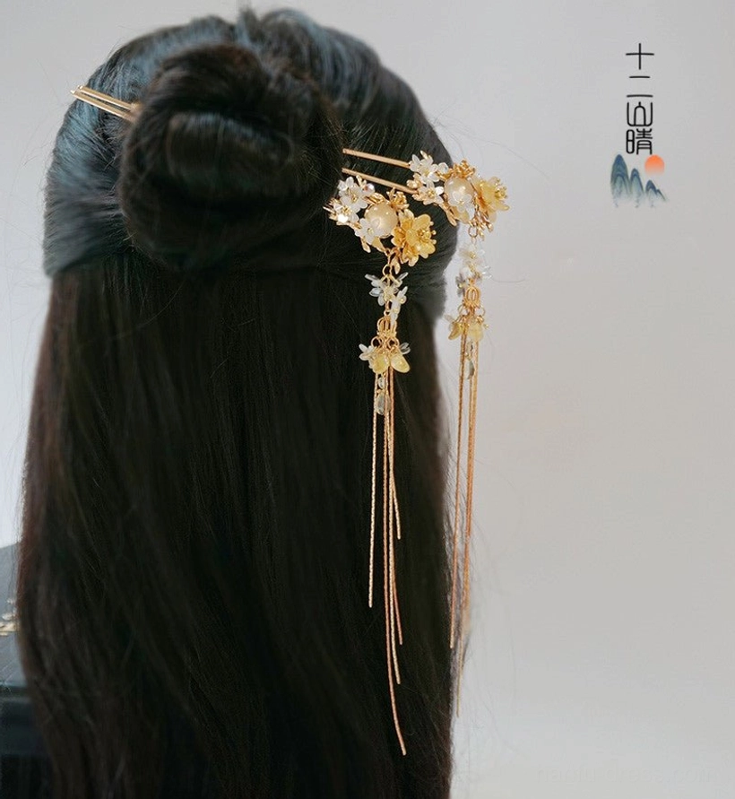 Back view of traditional Chinese topknot hairstyle decorated with Xiangling gold floral hair pins and long tassel chains