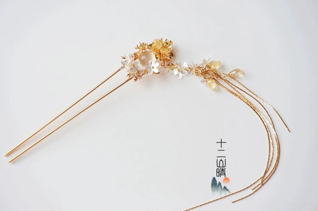 Single Xiangling Chinese style double-prong gold floral tassel hair pin with blue purple blossoms and hanging chains on white background