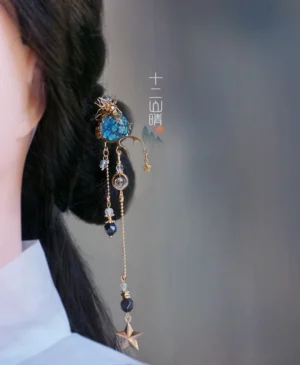 Xingyue starry sky Chinese hair stick worn in a coiled Hanfu hairstyle with galaxy blue bead, gold tone details, and long star tassel