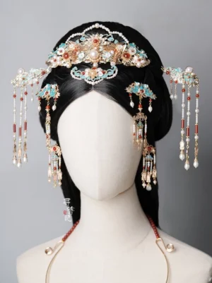 Traditional Chinese Hanfu hairstyle styling with an elegant blue cloisonne hair pin, pearl and red gemstone ornaments, gold-toned details, and long decorative tassels on a mannequin