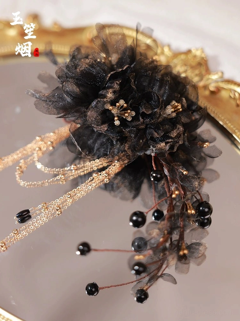 Flat lay of a traditional Chinese Hanfu hairpin with layered black flowers gold-toned centers chain tassels and dark bead accents