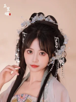 Woman wearing Xuepo light blue floral Hanfu hair pins with silver tassels, pearl-like beads, and traditional coiled hairstyle