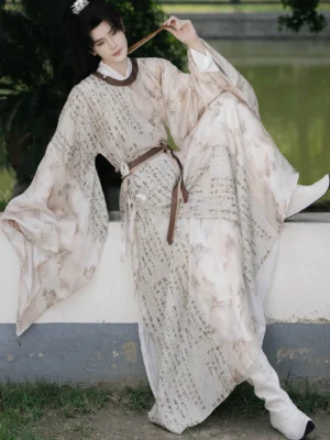 Male model wearing Yanchi Song Dynasty inspired hanfu robe beside a garden wall, showing flowing printed robe and brown waist belt