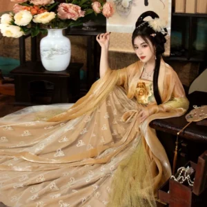 Yang Guifei inspired golden Tang Dynasty Heziqun Hanfu dress set shown in a three-quarter seated view with floral chest ornament and flowing embroidered skirt