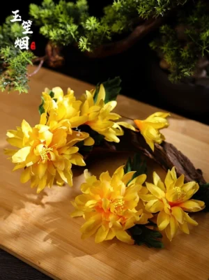 Top view of yellow artificial chrysanthemum hair ornaments with dark green leaves on a wooden board and pine branch background
