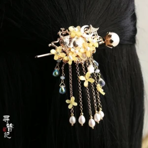 Yellow osmanthus Hanfu back hair pin shown in straight black hair with gold-toned metal, yellow flower charms, freshwater pearl pendants, blue glass bead tassels, and a large pearl accent
