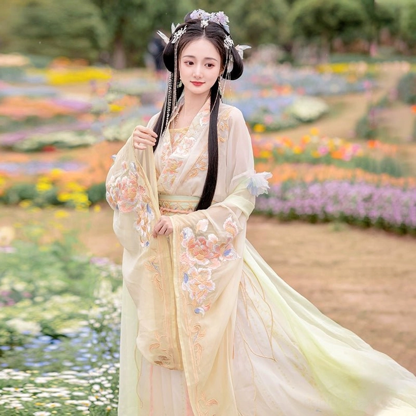 Front view of the yellow Wei Jin Dynasty Hanfu full set with an embroidered apricot-yellow top, flowing gradient skirt, traditional hair ornaments, and flower-field setting