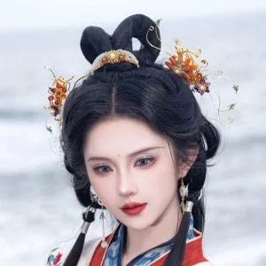 Close-up portrait of a model wearing gold-tone Yi Huan Hanfu hair accessories with floral ornaments and dangling earrings beside the seaside