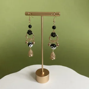 Yin Yang Tai Chi Chinese hook earrings displayed on jewelry stand with black beads floral details gold tone hardware and hollow bell drops