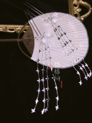 Yinchuan silver floral tassel hair pins displayed on a pink Chinese folding fan with delicate flower ornaments and long star pendant chains