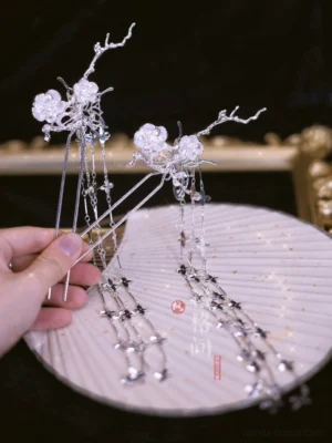 Close-up of Yinchuan silver Hanfu hair pin held by hand showing crystal flower detail branching metal frame and cascading tassel chains