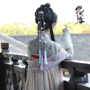 Model wearing a traditional Chinese Hanfu hairstyle with Yingliang back hair pin long pearl bead chains pastel flower charms and blue purple tassels