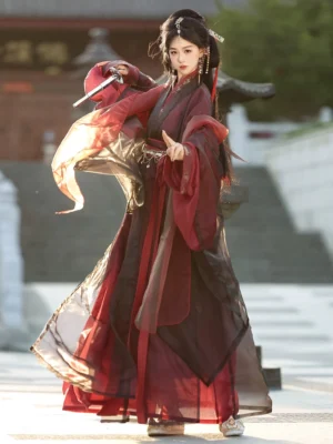 Yuji Lament Wei Jin Dynasty Hanfu robe in deep red and black with sheer layered fabric, wide sleeves, ornate waist belt, and floor length skirt worn in a classical Chinese garden